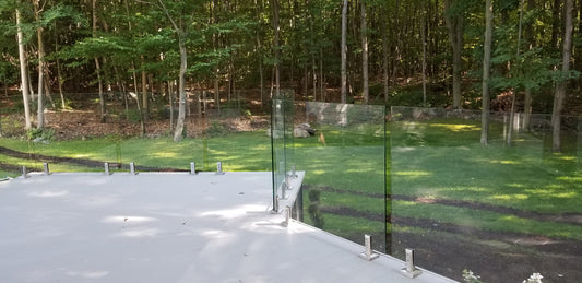 Rampe de verre clair 12mm sur balcon de béton offrant une vue sur la forêt
